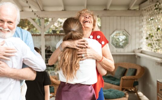 A heartwarming reunion with family members hugging and smiling in a cozy indoor setting.